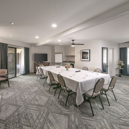 A modern conference room with a long table, multiple chairs, a fireplace, and a spiral staircase in the corner.